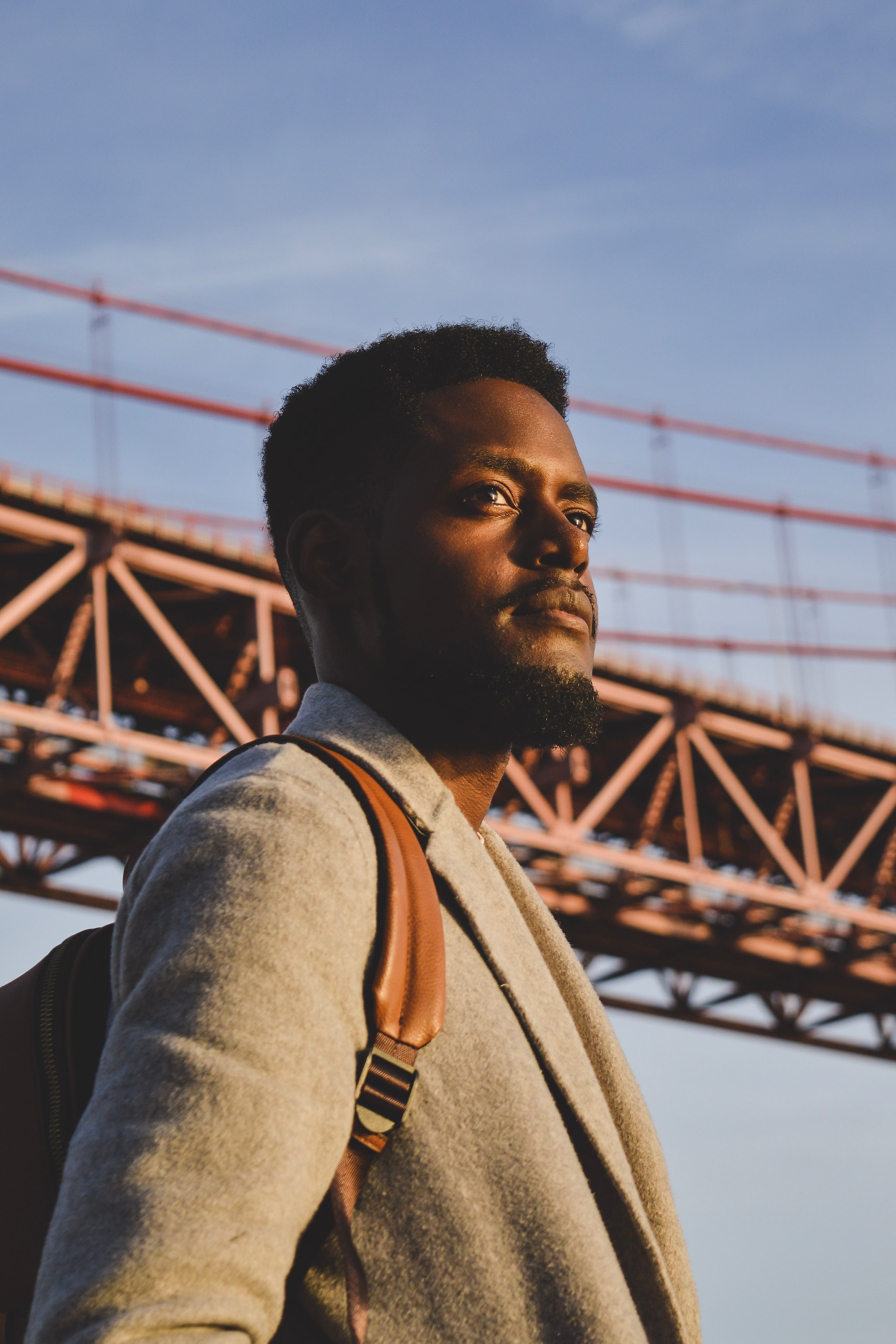 Man with backpack standing in front of a bridge